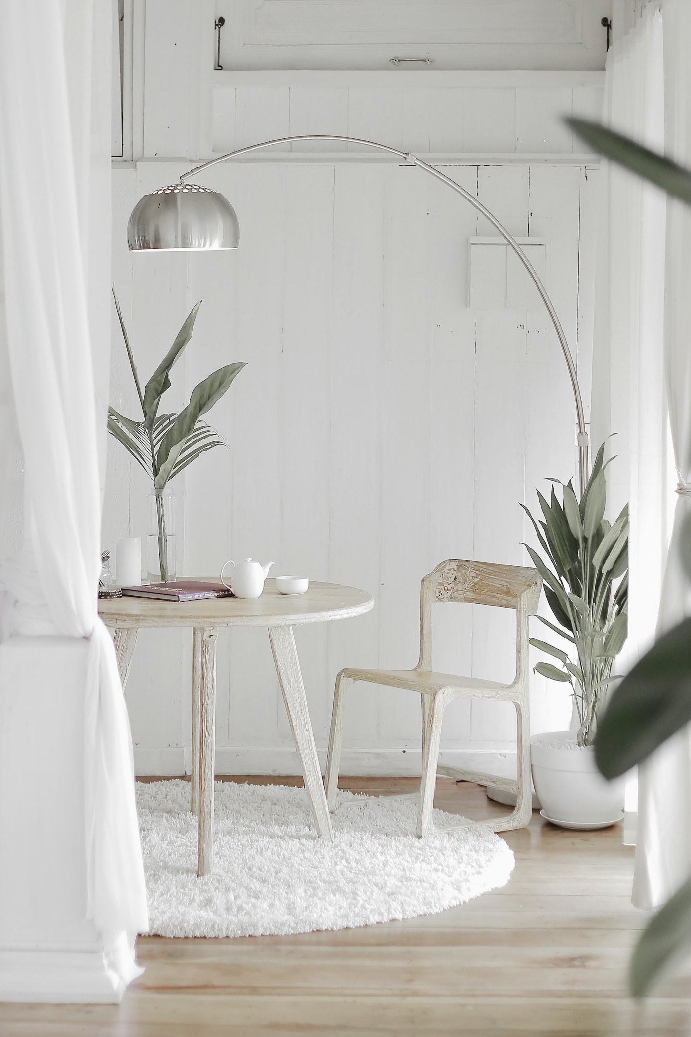White reading nook with a small table and plants